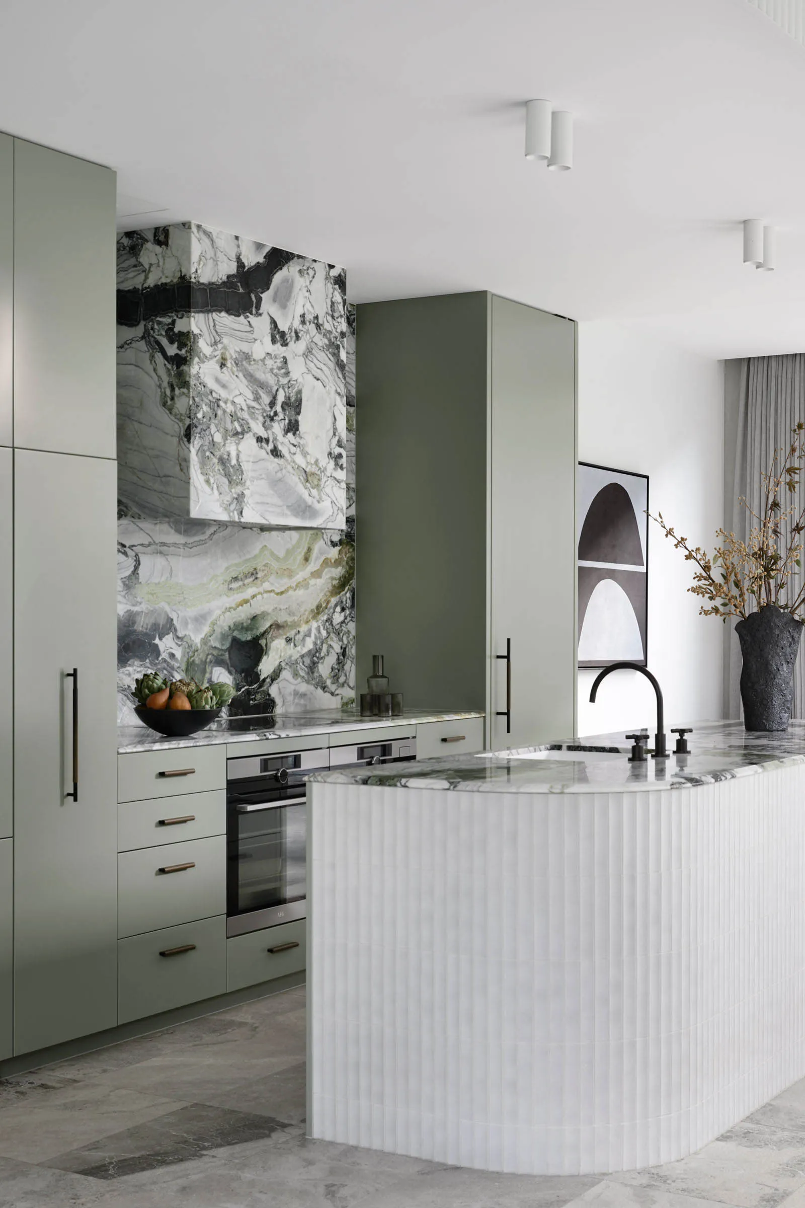 A sleek, minimalist kitchen featuring marble countertops and backsplash, modern appliances, and a curved island.