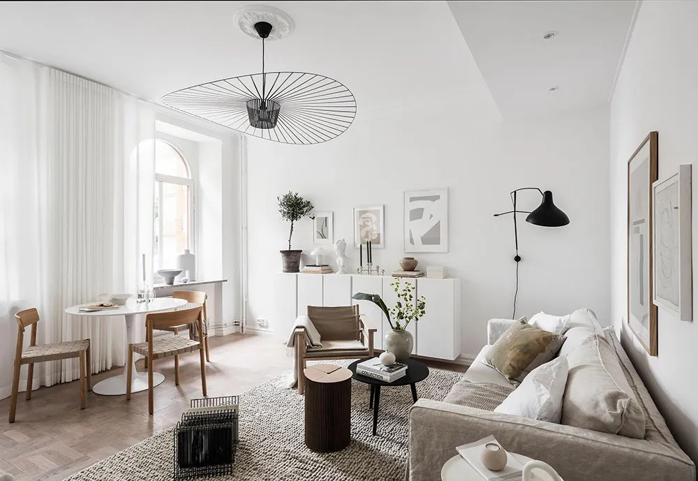 A minimalist living room with a concrete floor, white walls, and a large window.