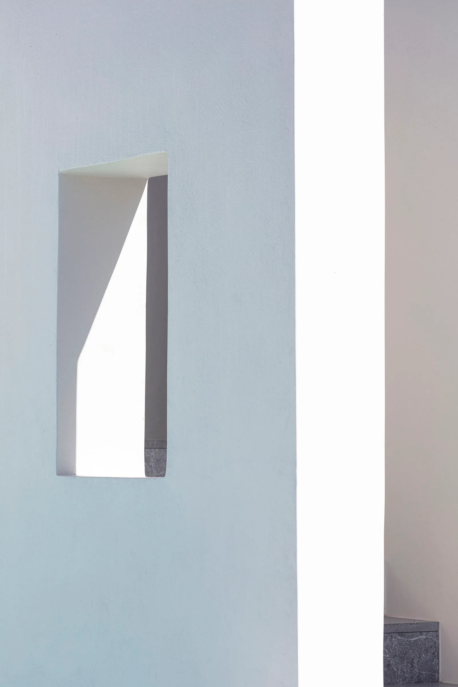 A minimalist white concrete architectural detail with a rectangular cutout.