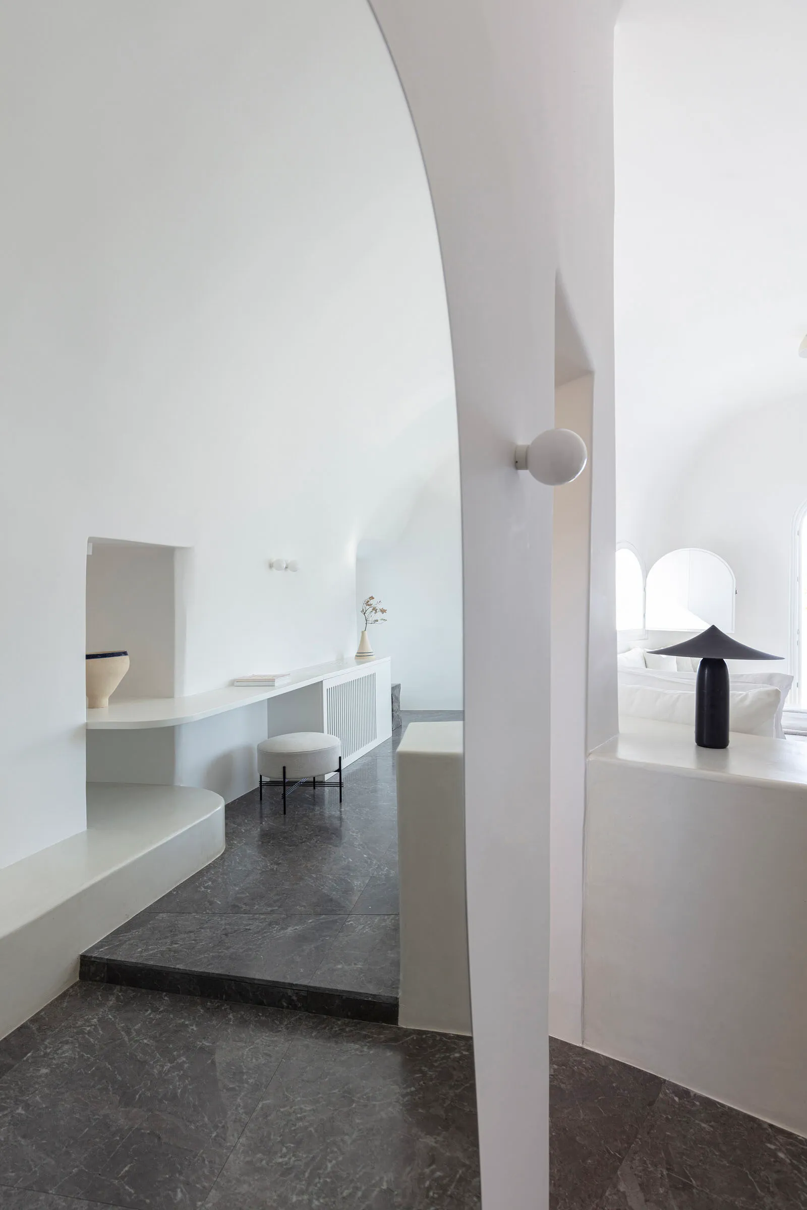 A minimalist interior with white marble flooring and walls, featuring a modern design with clean lines and a single black lam