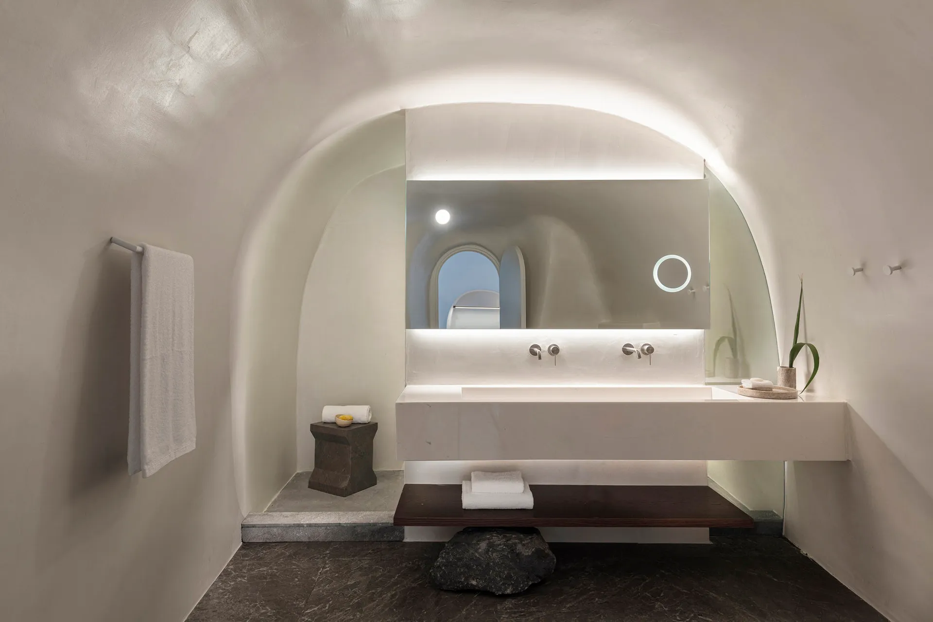 A modern bathroom featuring white stone surfaces and minimalistic design.