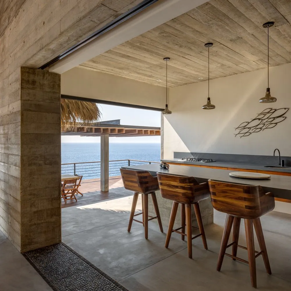 Modern minimalist residential kitchen featuring concrete and terrazzo materials with ocean views.