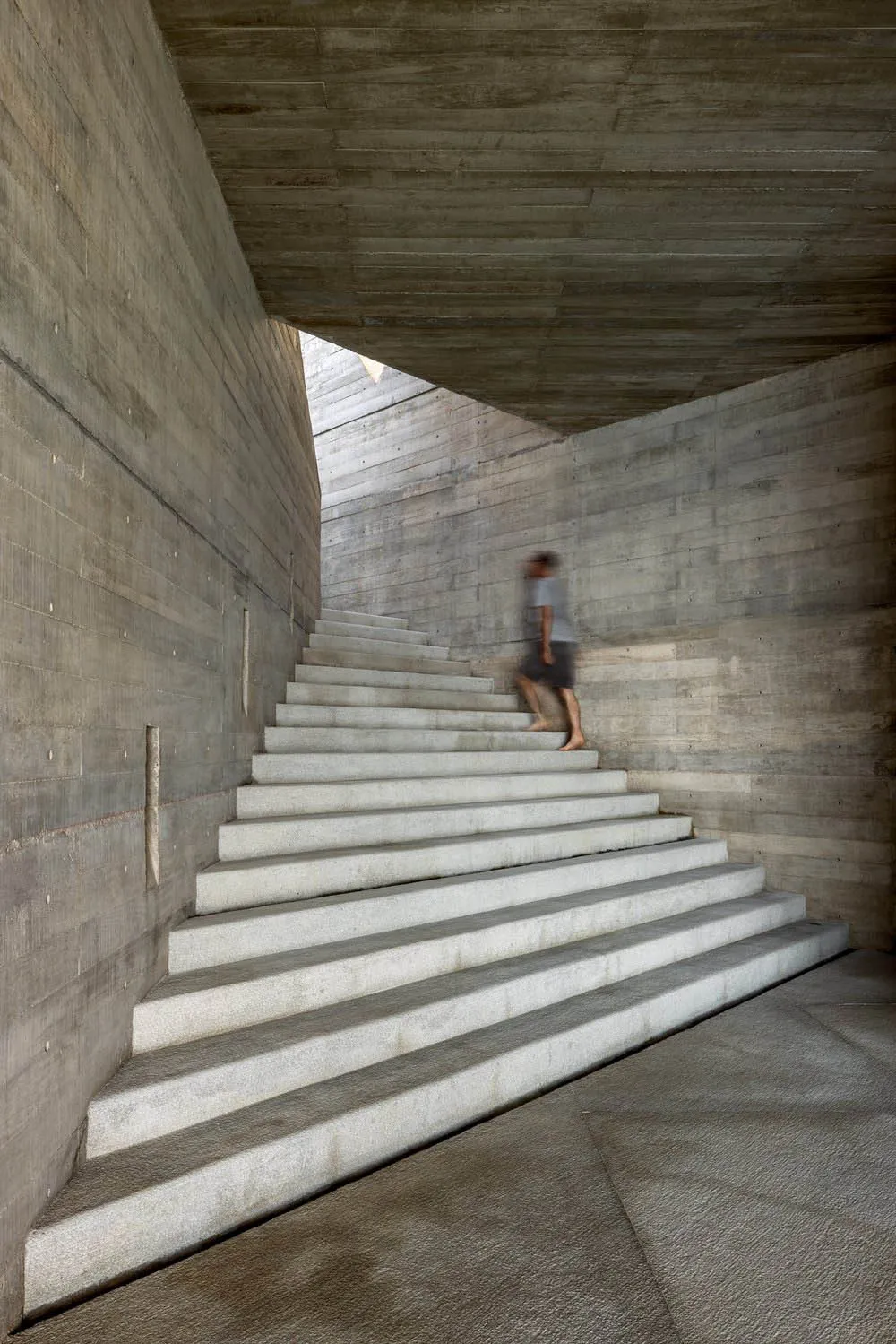 A modern, industrial-styled staircase constructed from concrete, featuring a minimalist design with smooth, clean lines.