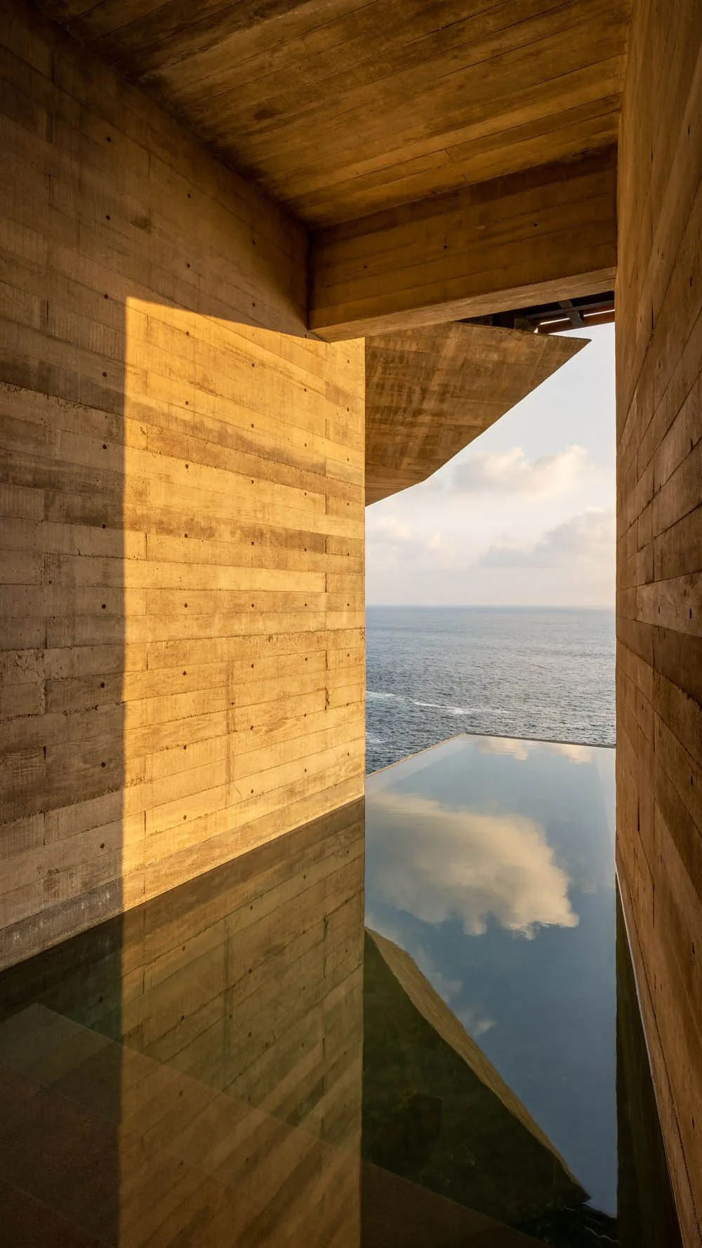 Modern interior with wooden walls and glass enclosure overlooking the ocean.