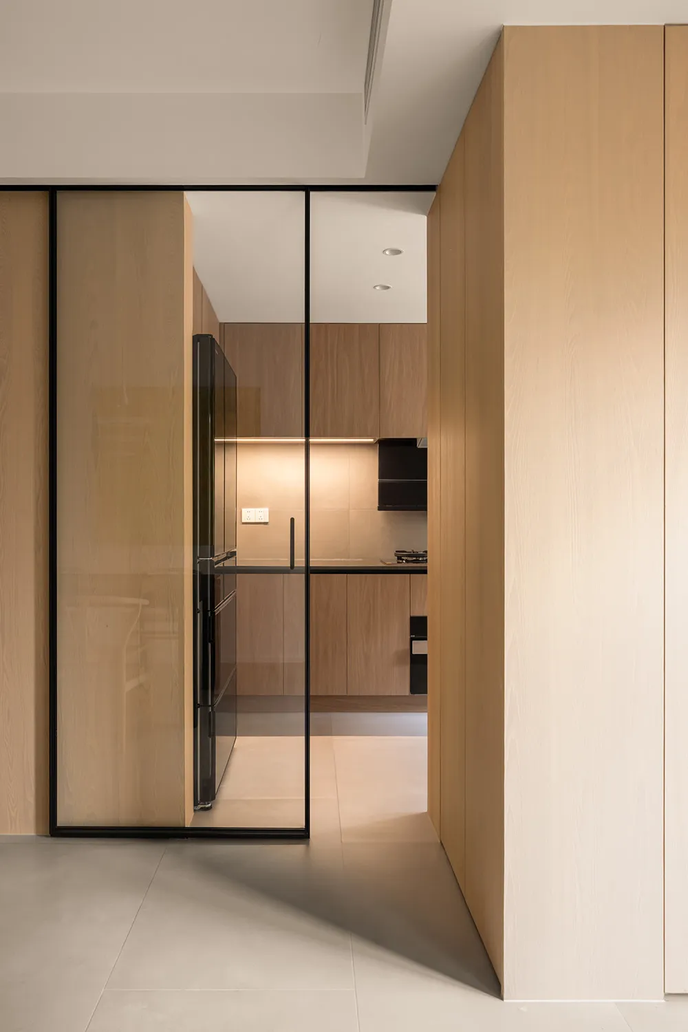 Modern, minimalist residential kitchen with wood cabinetry and flooring.