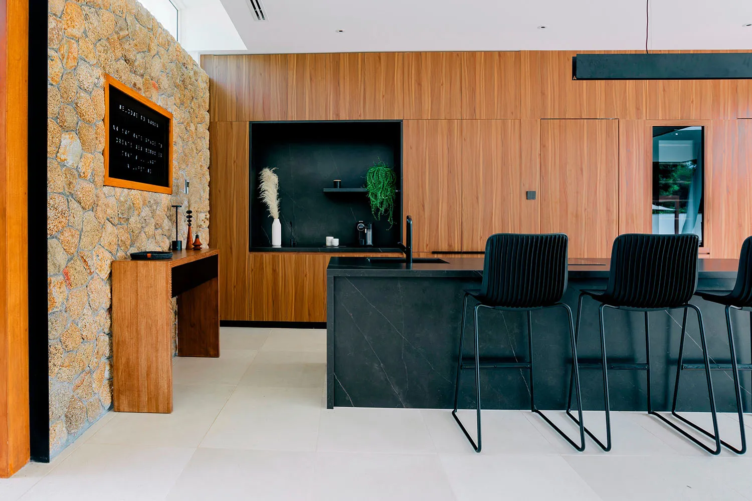 Modern kitchen interior featuring wood-paneled walls and black marble countertops