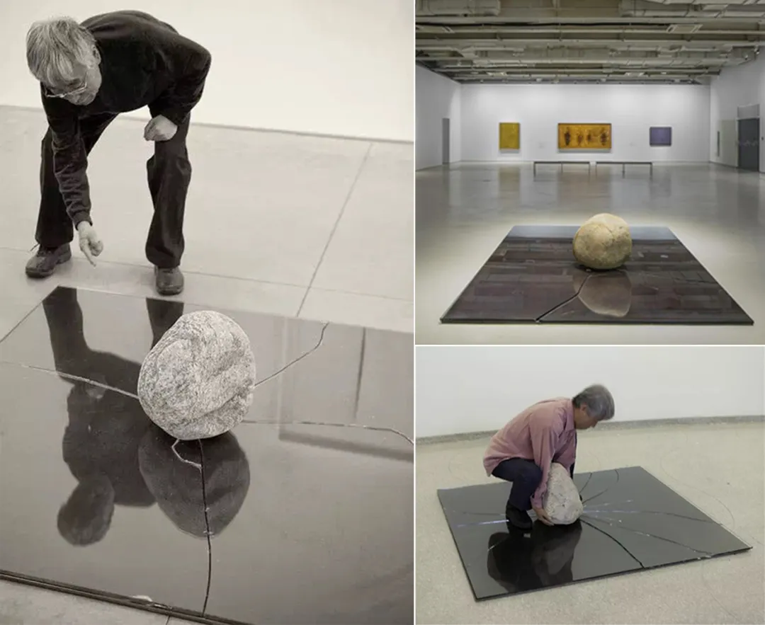 A reflective metal floor displays a large spherical stone, with a person interacting with it in a museum.