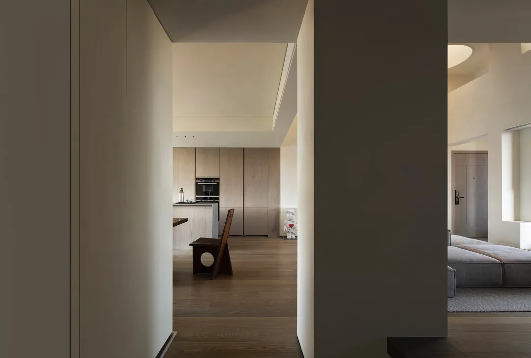 A modern minimalist kitchen featuring light-colored wooden cabinets and a wooden dining table.