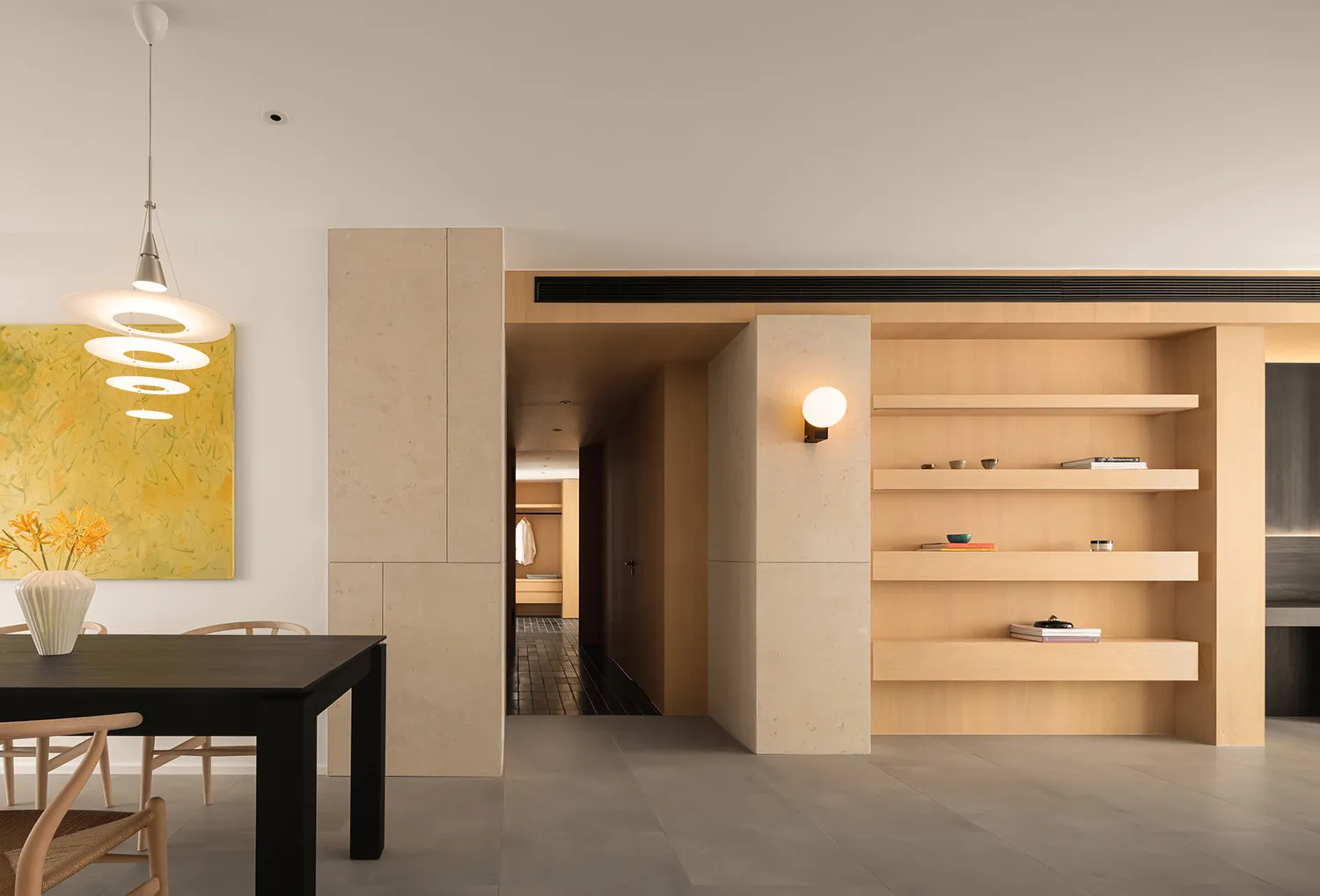 Modern minimalist dining room featuring a concrete floor, wooden shelves, and a black dining table.