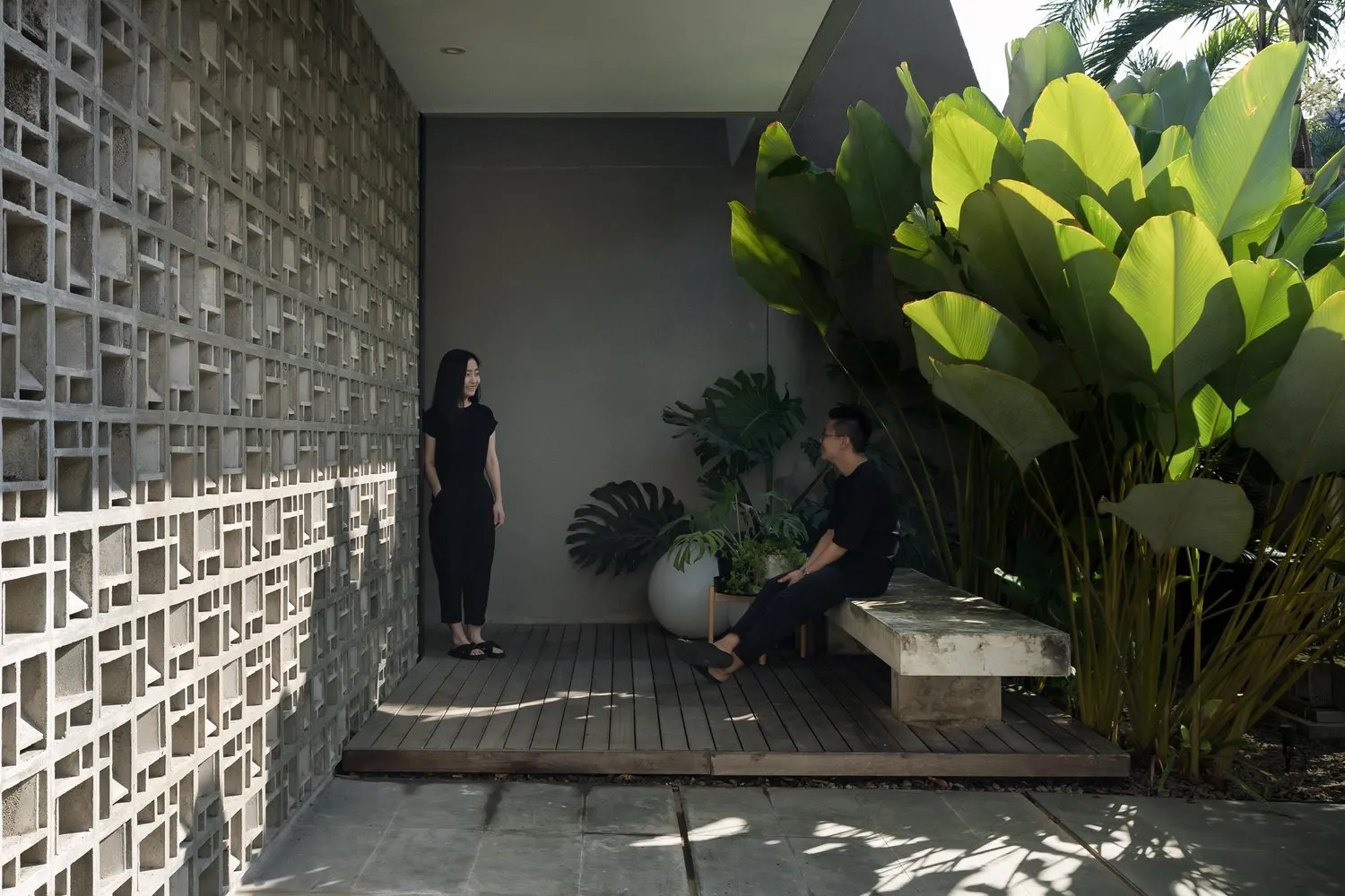 A modern concrete veranda with a woman and a man sitting on benches.