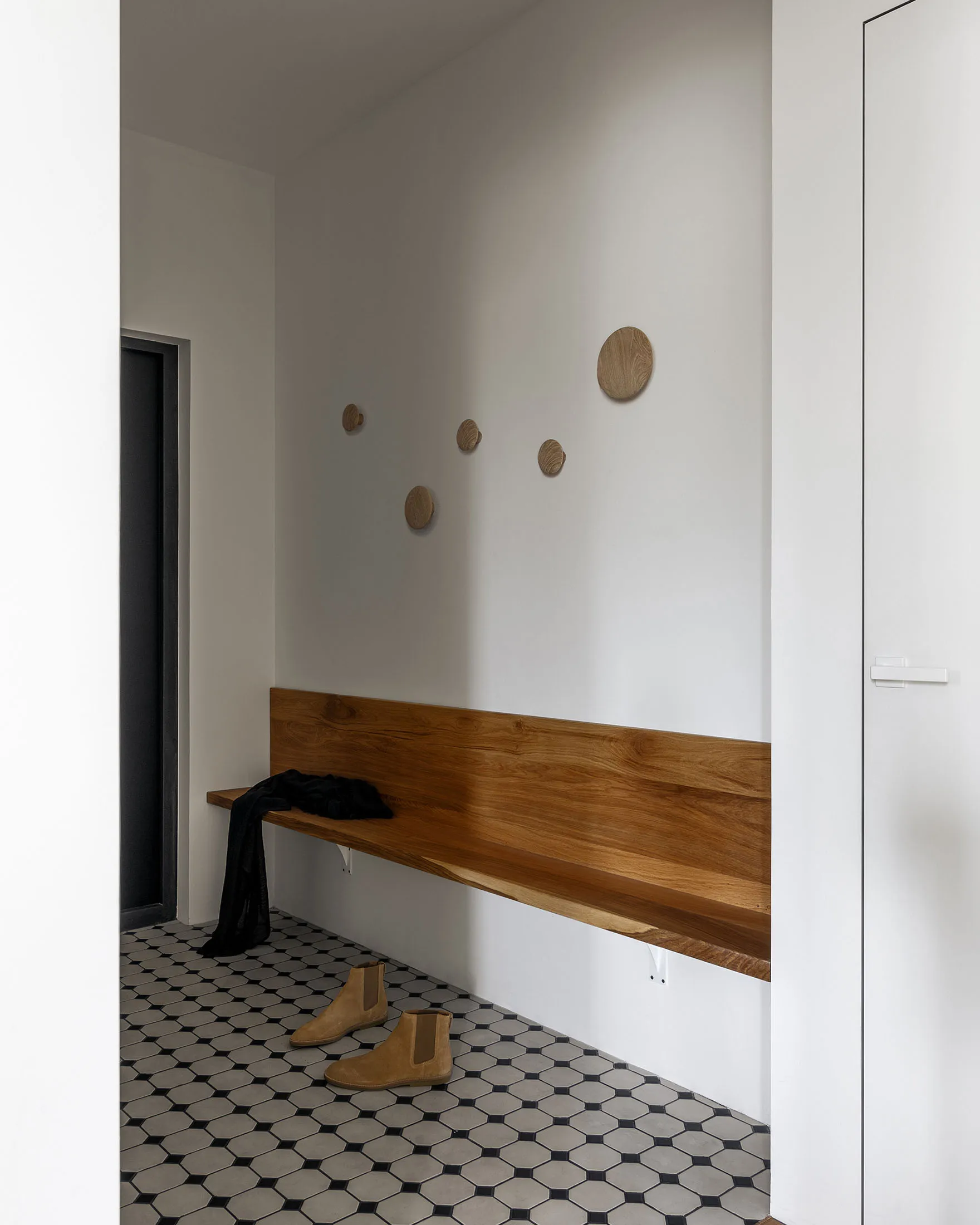 Entryway featuring a minimalist design with a wooden bench and ceramic tiles