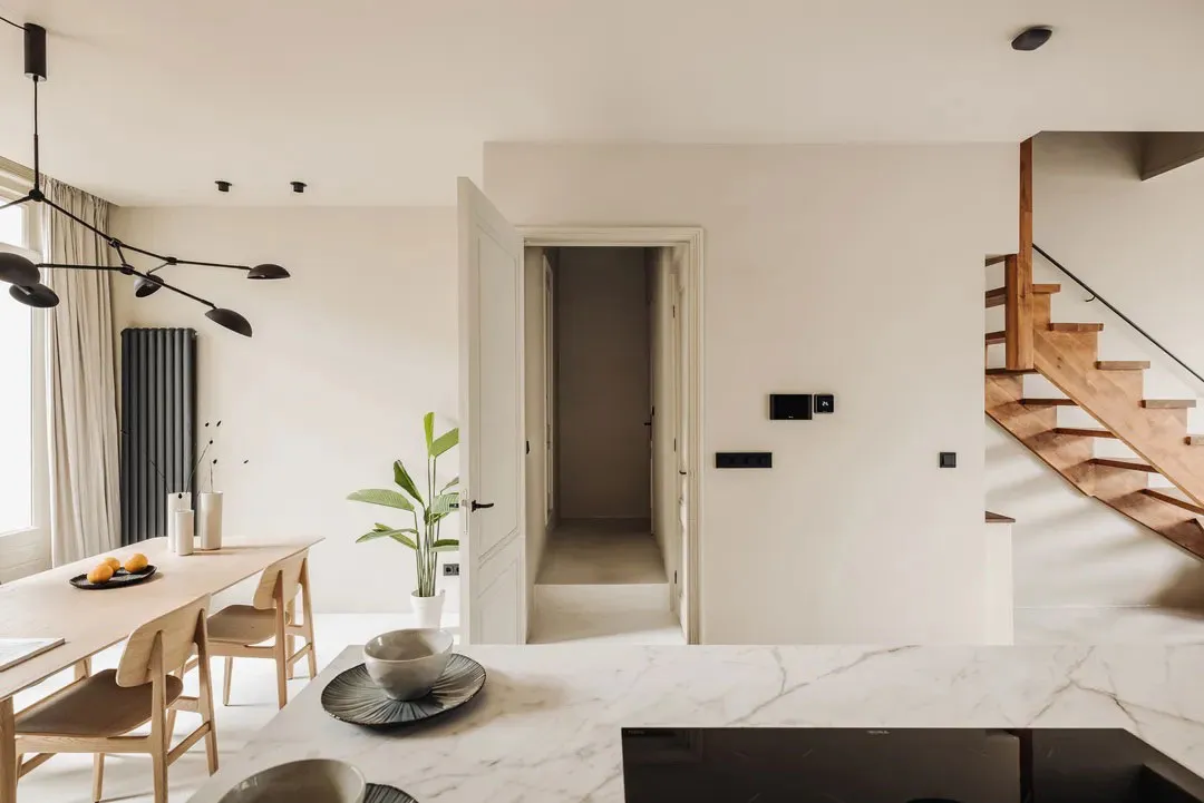 Modern residential interior featuring a minimalist design with a marble staircase and a central island kitchen.
