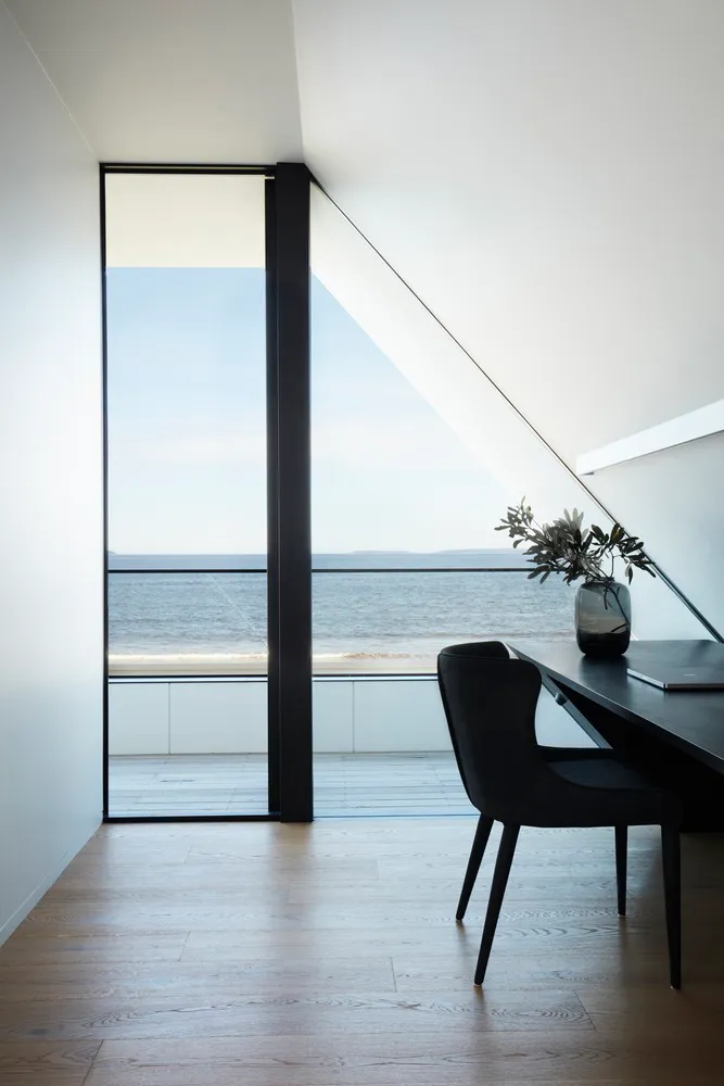 Modern home office with glass window overlooking the ocean.