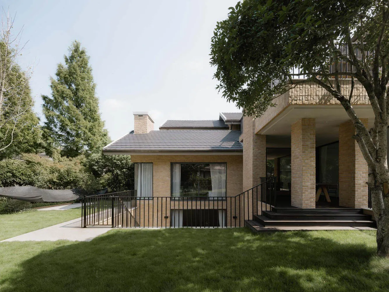 Modern house exterior with brick, glass, and wood materials in the backyard.
