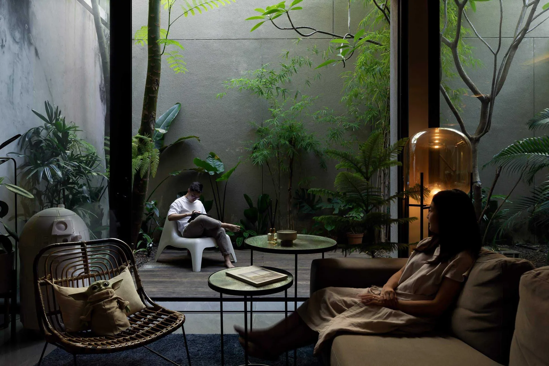 A modern living room with wooden furniture, concrete walls, potted plants, and natural lighting.