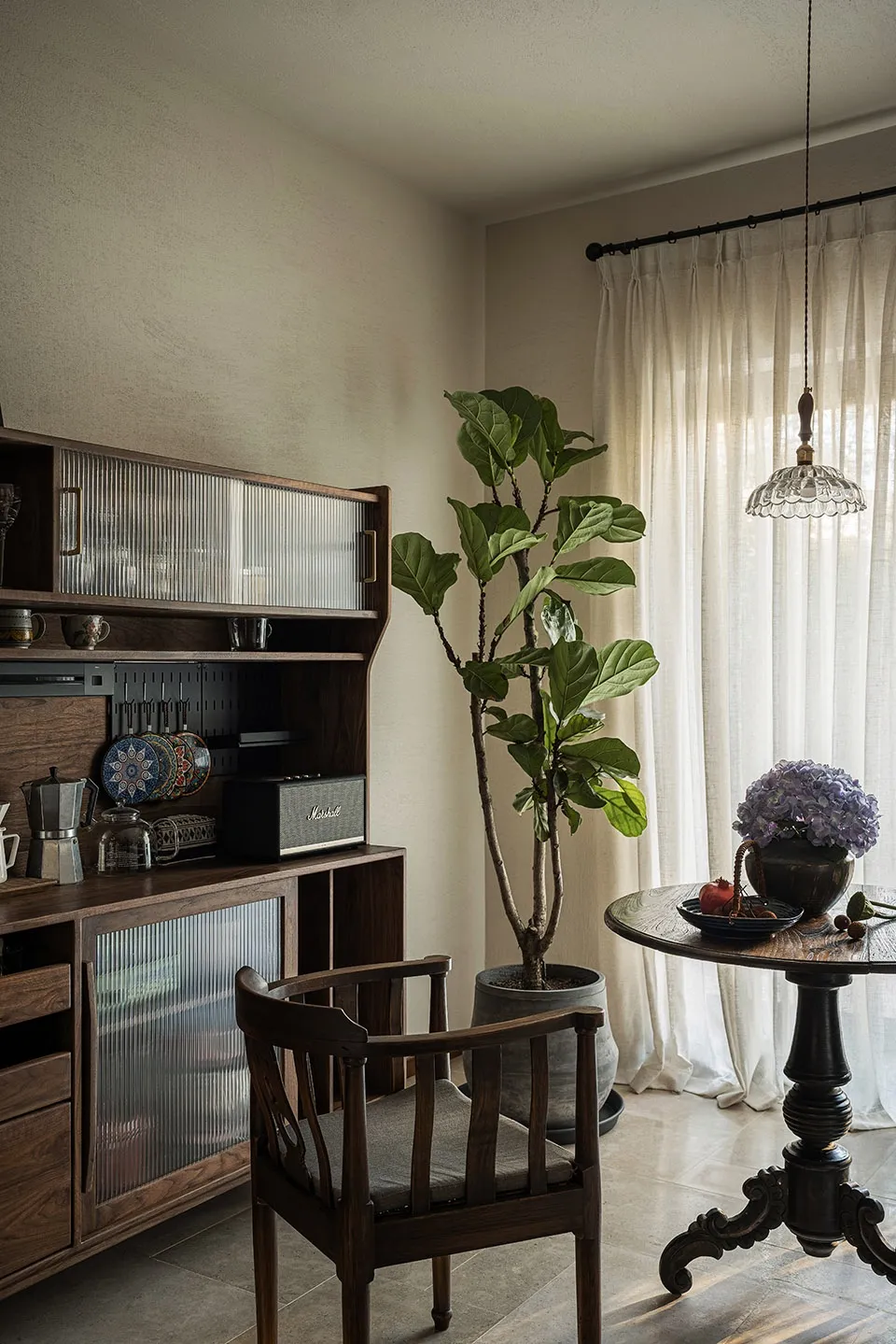 A modern living room featuring a large potted plant, wooden furniture, and a wooden cabinet with glass panels.