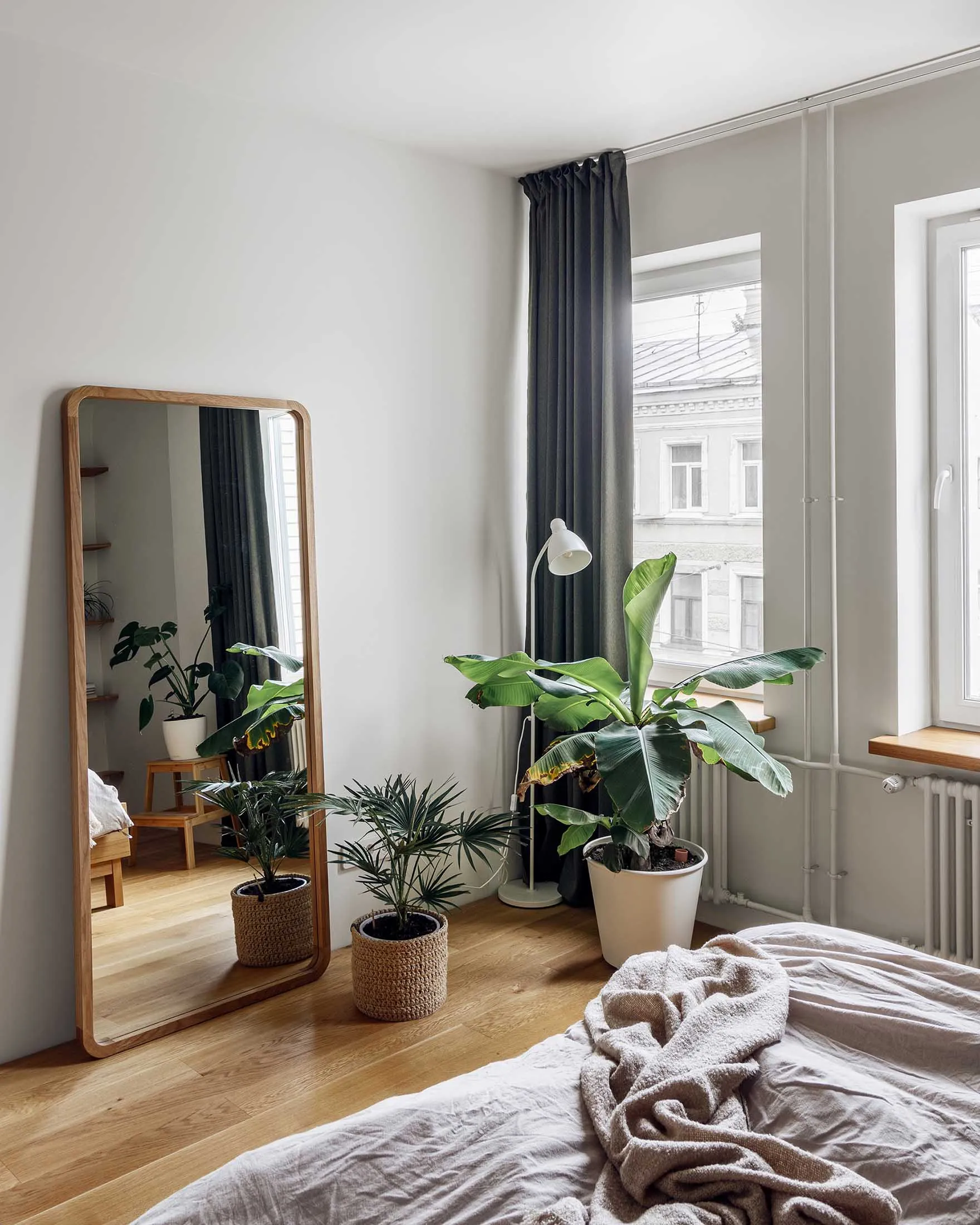 Minimalist bedroom featuring plants and a large floor mirror.