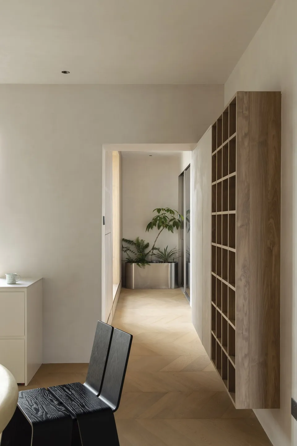 Interior design of a modern, minimalist corridor featuring wood flooring and a contemporary bookshelf.