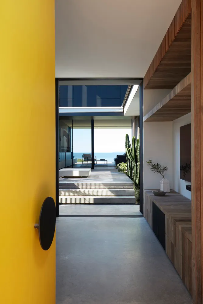 Modern minimalist living room with concrete, wooden, and glass fixtures.