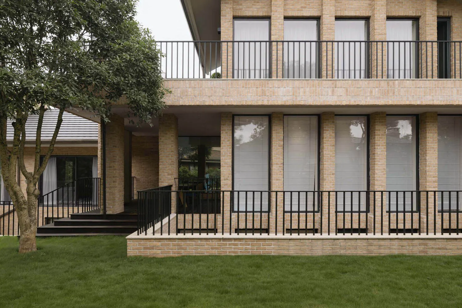A modern house exterior made of brick with large windows and a balcony.