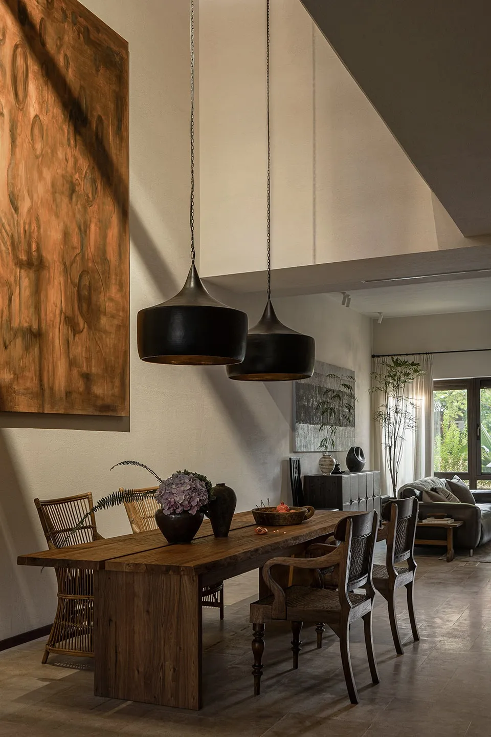 Modern, industrial-style dining room with a large wooden table, pendant lights, and abstract wall art.