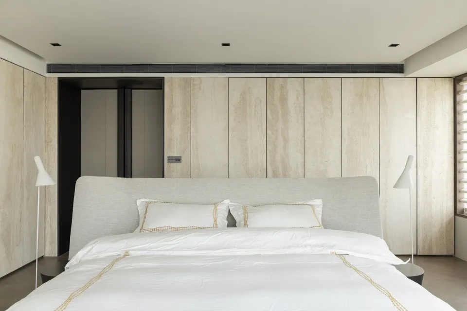 Modern bedroom with light wood texture walls and a neatly made bed.