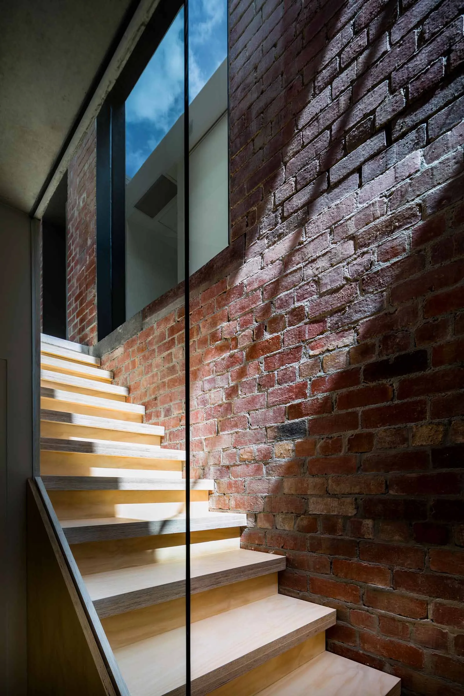 Modern staircase with wooden steps and brick walls