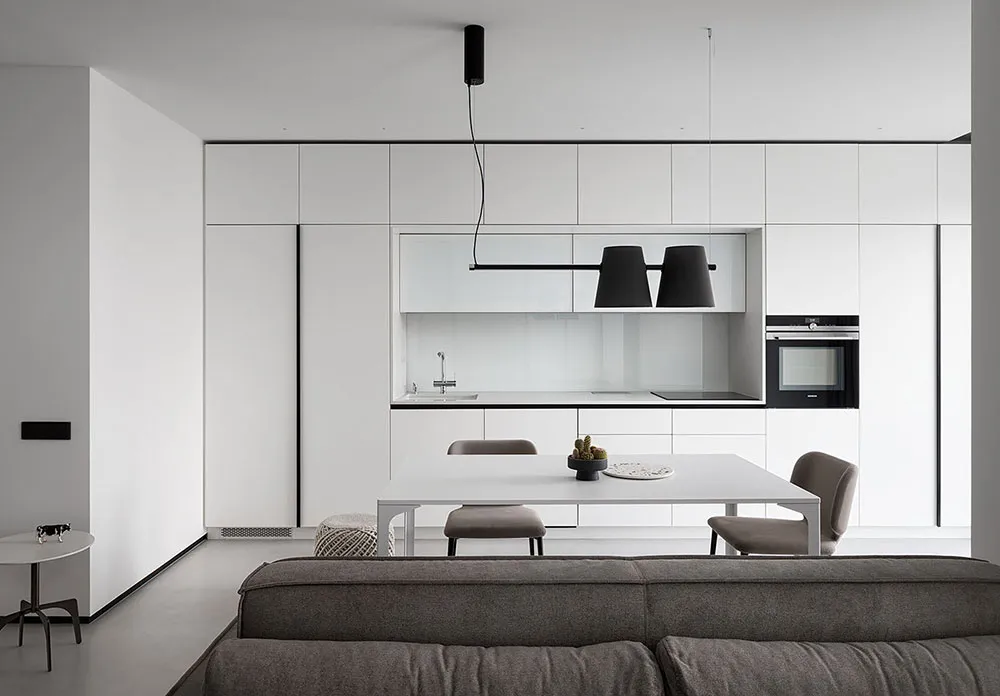 A modern, minimalist kitchen with white cabinets and black accents.