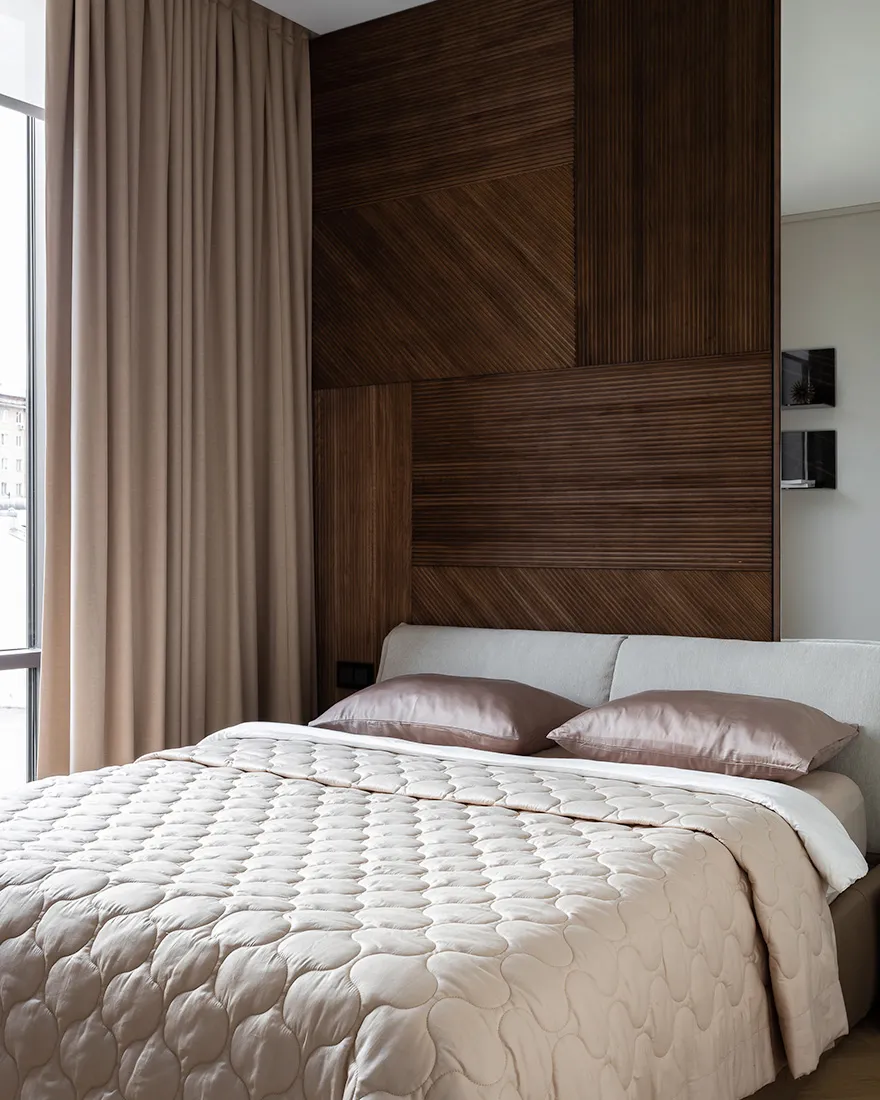 Modern minimalist bedroom with wooden headboard and light-colored bedding.