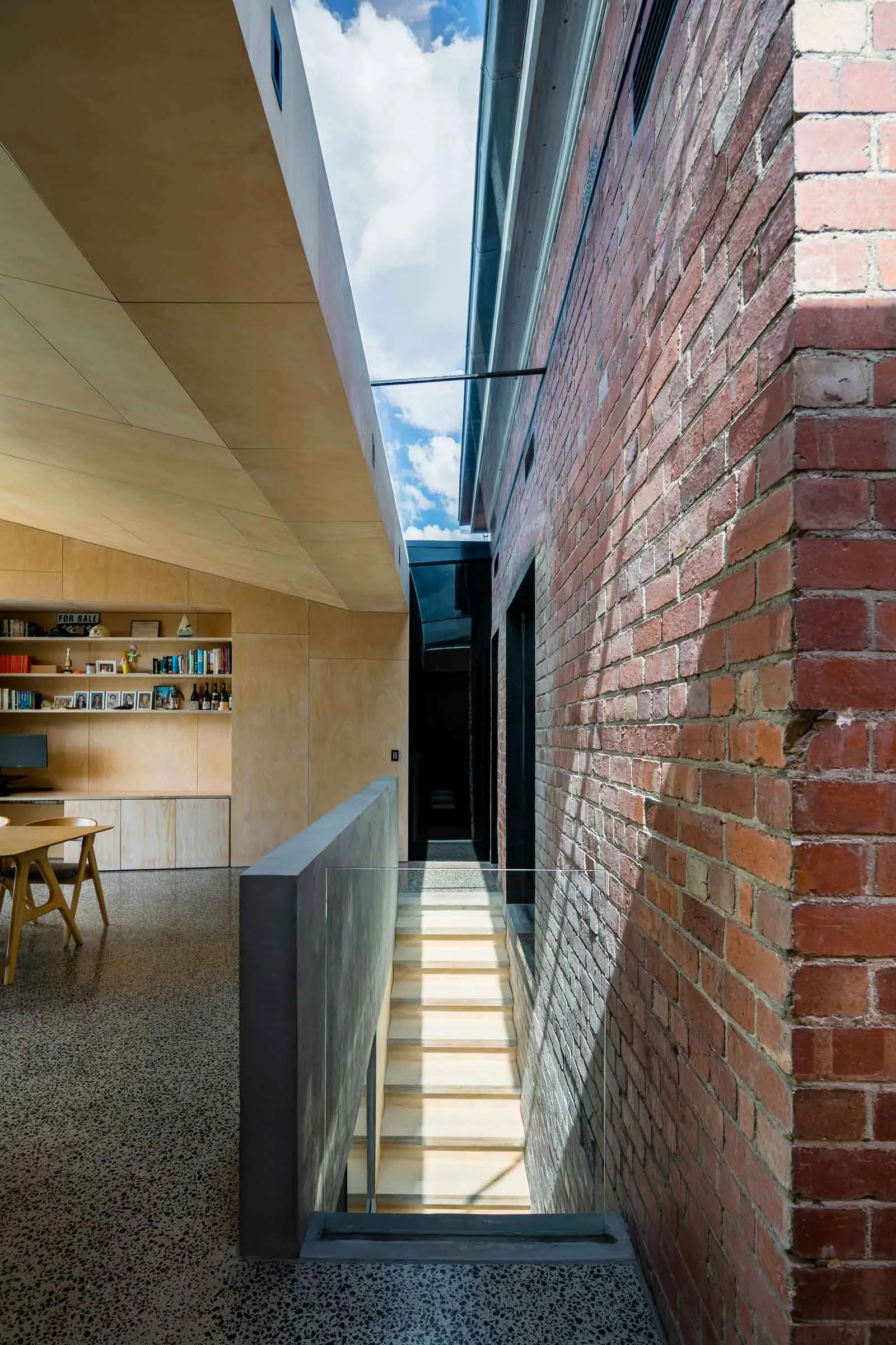 A modern industrial residential staircase features brick walls and a concrete floor.