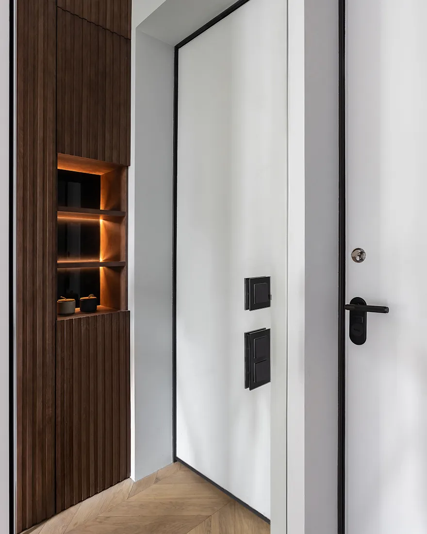 A modern doorway featuring minimalistic door design, LED lighting, and sleek storage shelves with a wooden finish and metalli