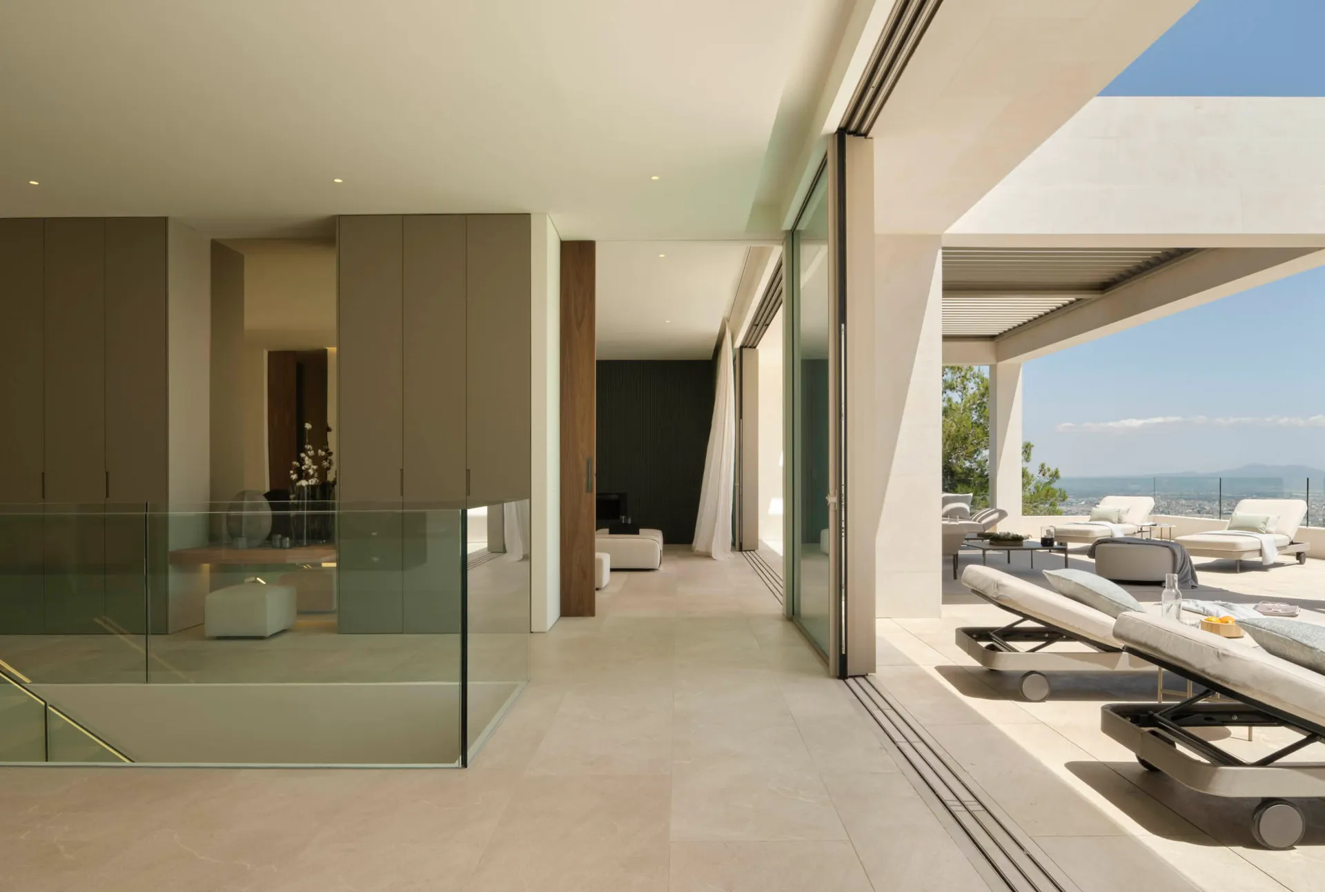 Contemporary living space with glass walls and modern furniture, featuring a comfortable lounge area and a stunning outdoor t