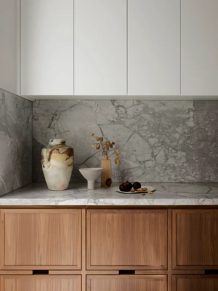 A modern kitchen with marble countertops and wooden cabinets.