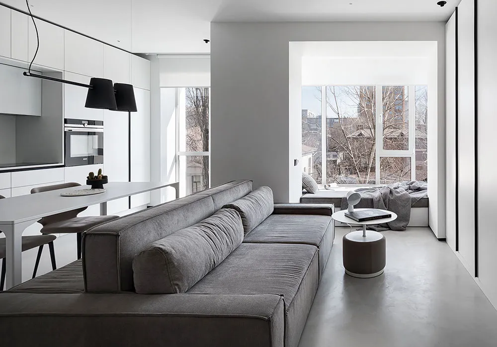 Modern living room with a concrete floor, a gray sectional sofa, and a minimalist design.