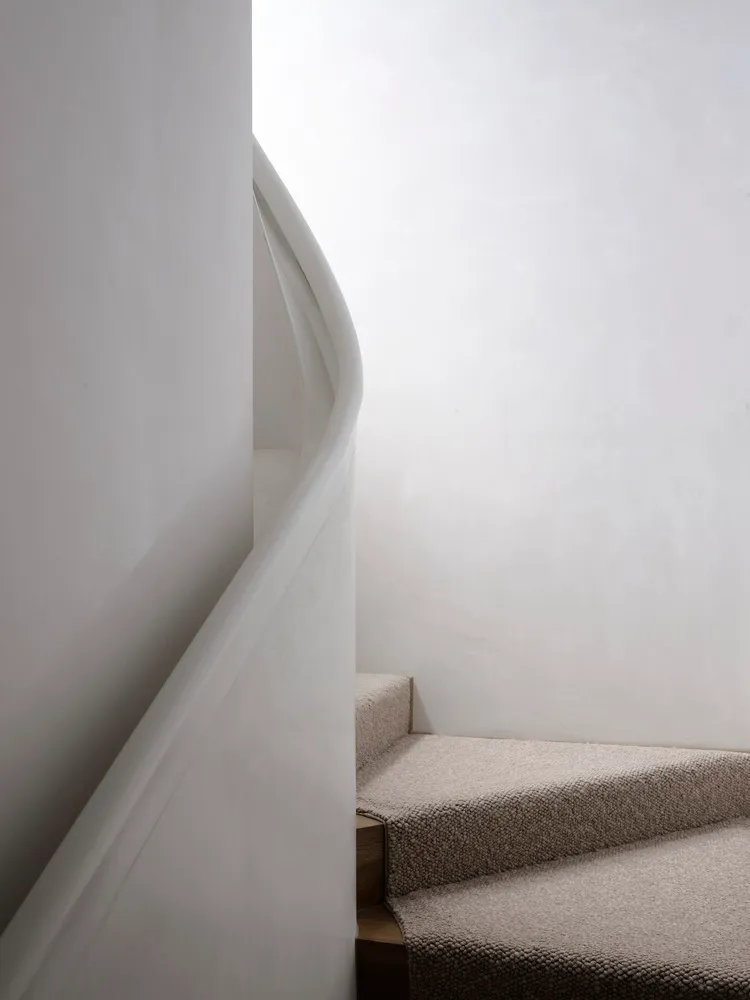 Modern staircase with neutral textiles in a white room