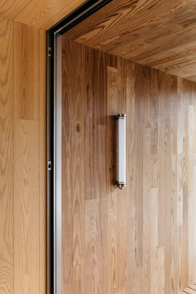 A close-up view of a wooden door with a sleek, white handle.