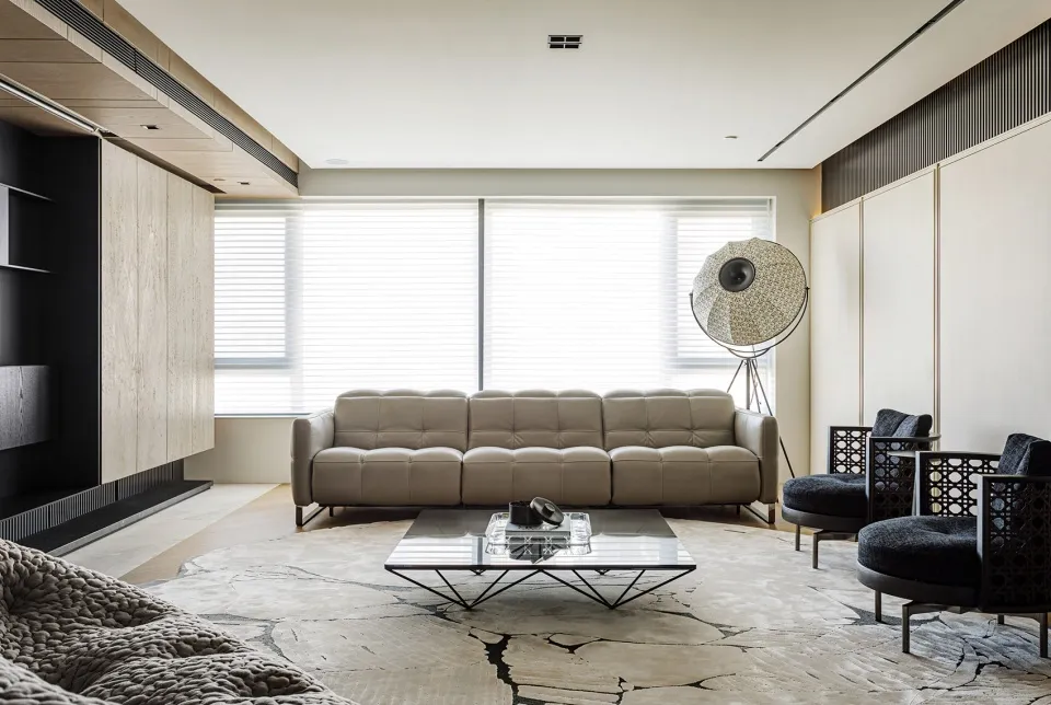 A modern living room featuring a leather sofa, metal coffee table, and a geometric floor lamp.