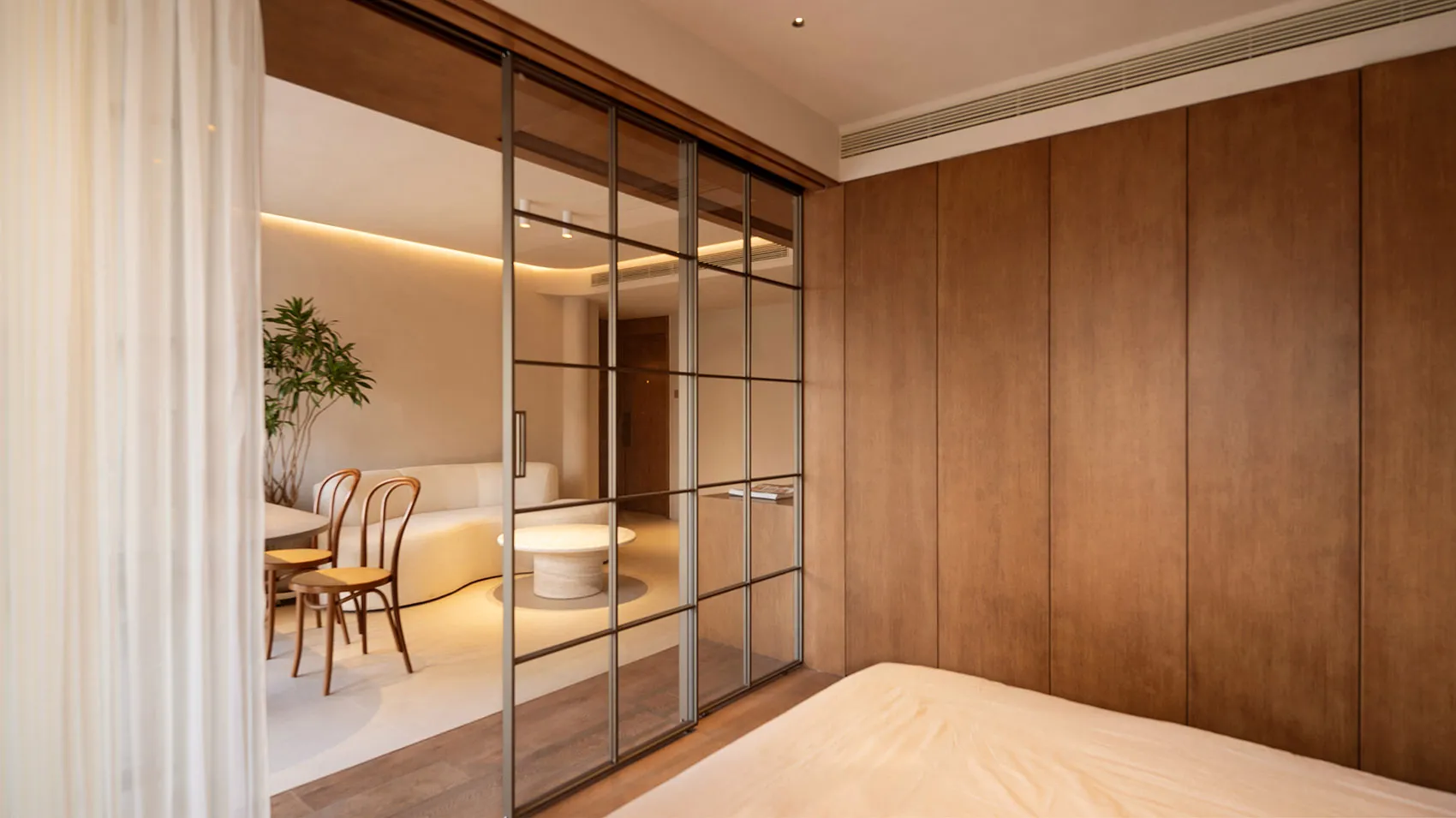 A minimalist bedroom with wooden paneling and a large bed.