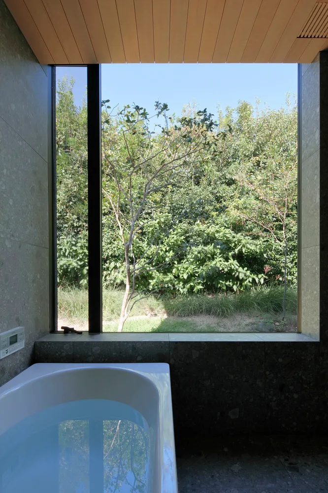 A minimalist bathroom featuring a glass window overlooking greenery.