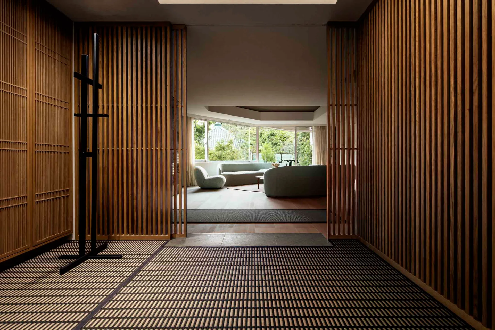 A minimalist residential interior featuring wood paneling, textiles, and concrete flooring.
