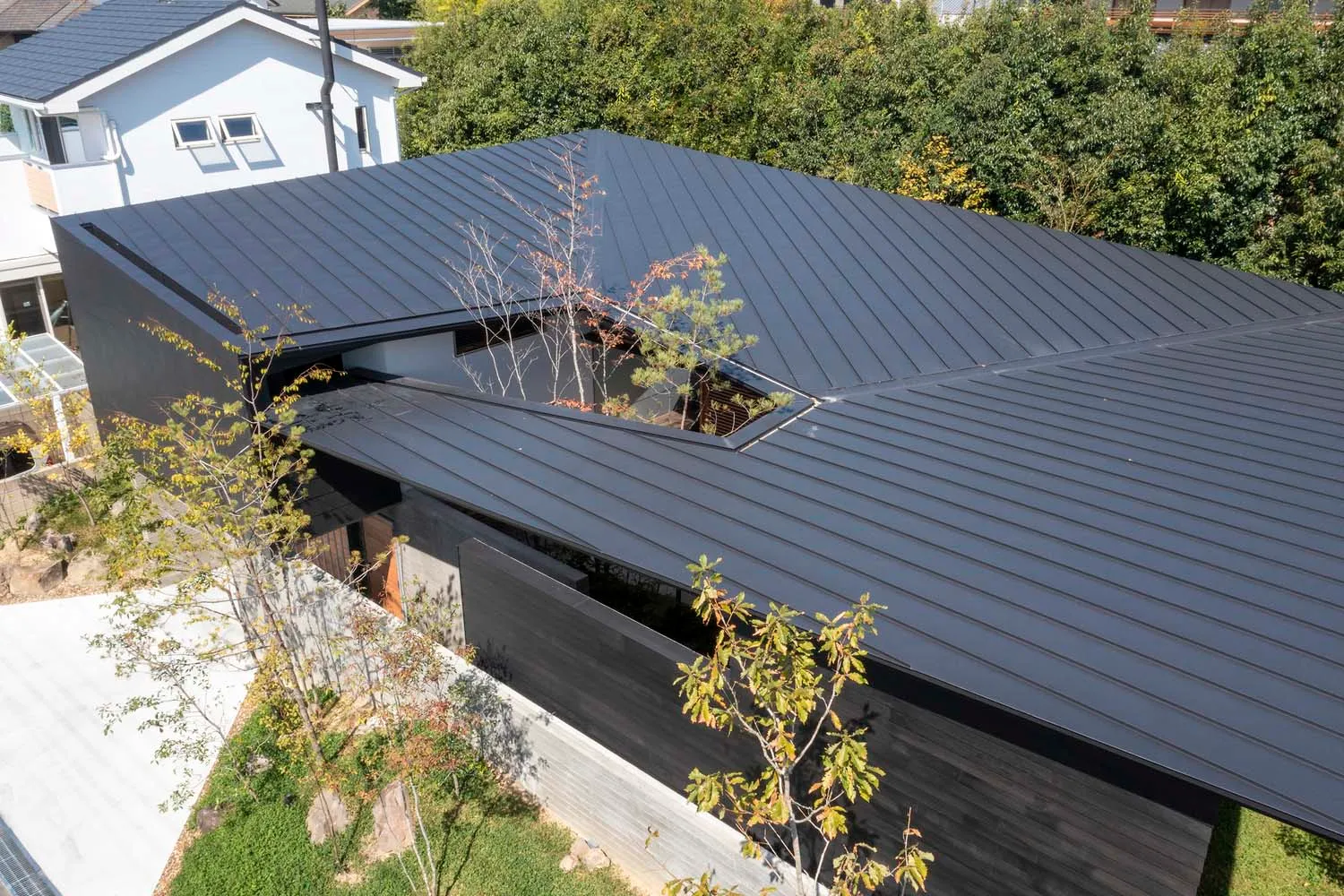 A modern house with a metal roof on a hillside.
