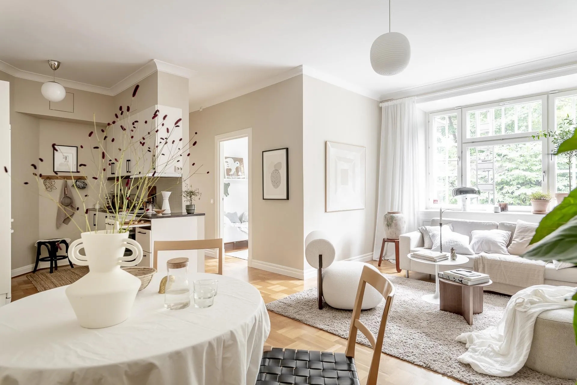 A modern minimalist residential interior with a neutral color palette, featuring a spacious open-plan layout with kitchen, di