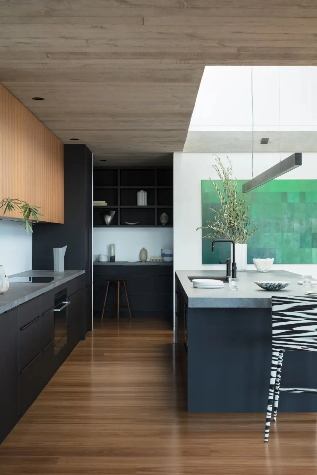 Contemporary residential kitchen featuring minimalist design, concrete countertops, wooden cabinets, and stone accents.
