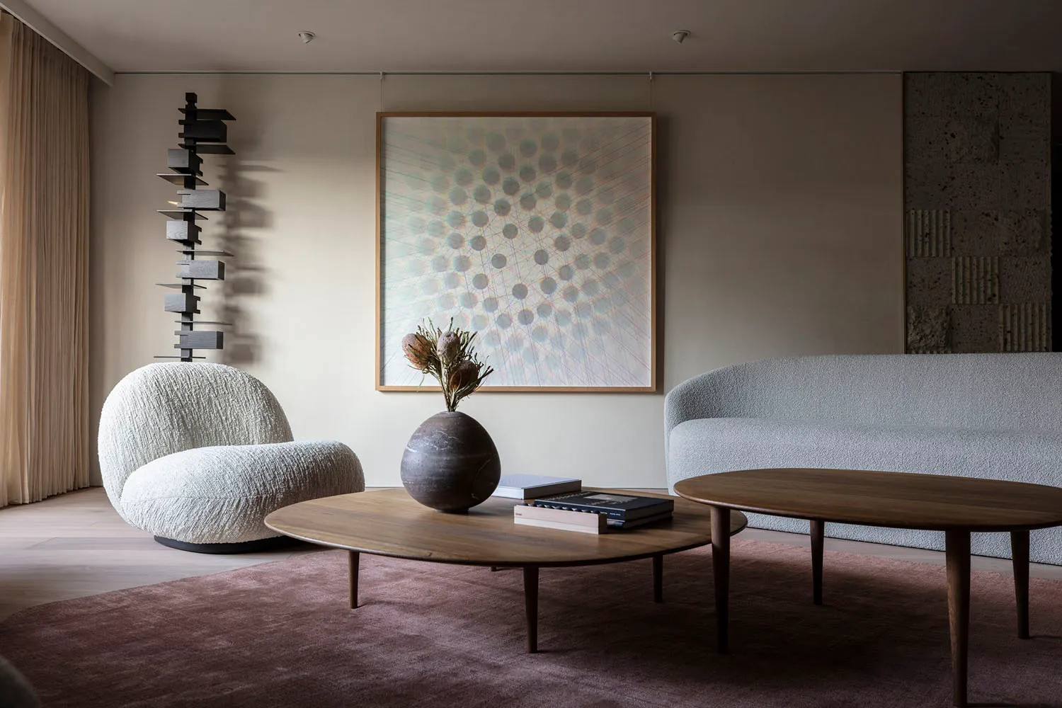 A modern minimalist living room featuring a marble coffee table, wooden sofa, and plush fabric chairs.