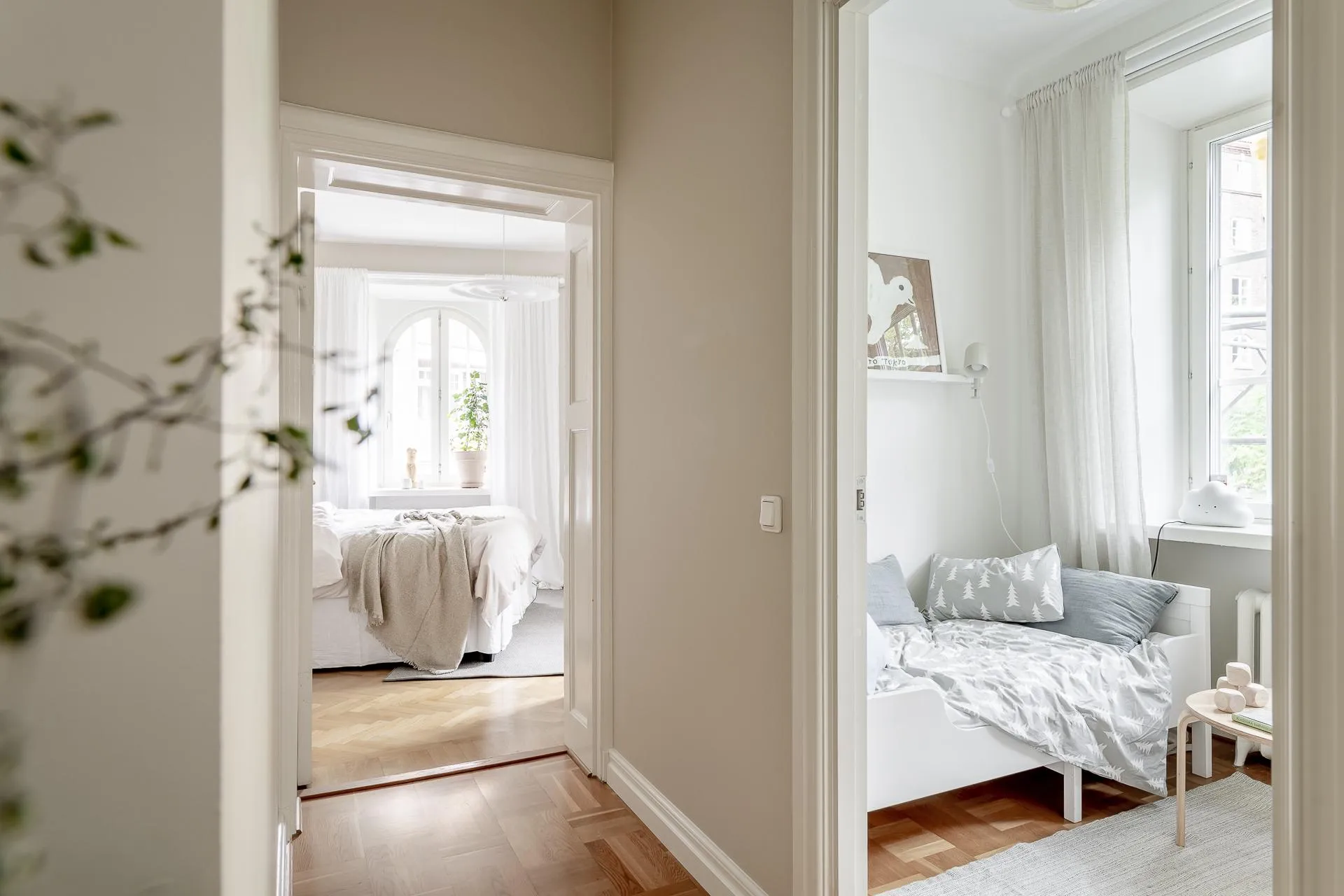 A modern minimalist bedroom with white furniture and wooden floors.