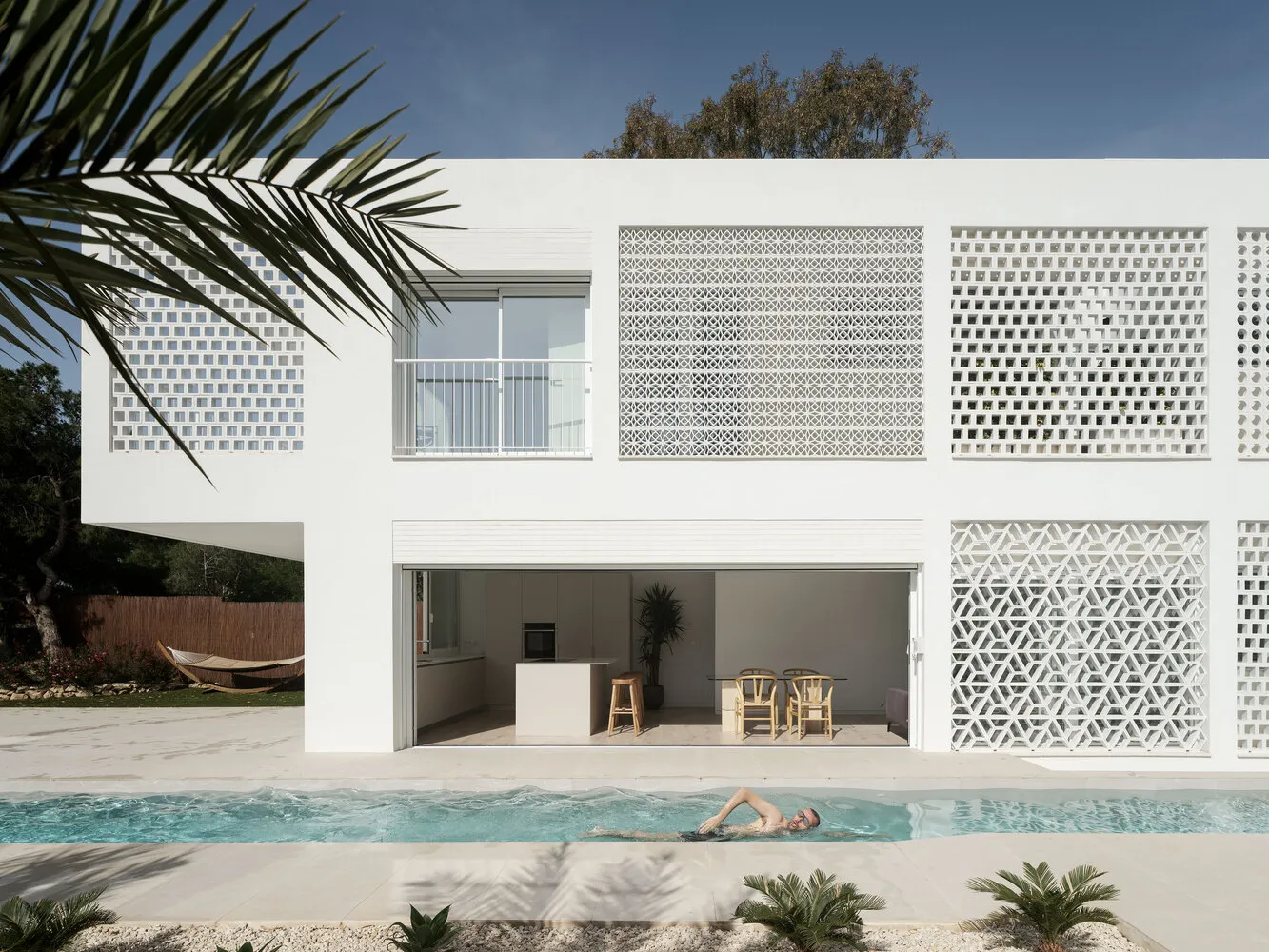 Modern residential building with a white, concrete exterior featuring large windows and geometric patterns.