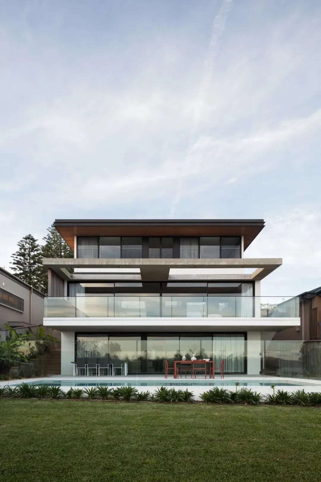 Two-story modern residential building with glass and concrete exterior materials