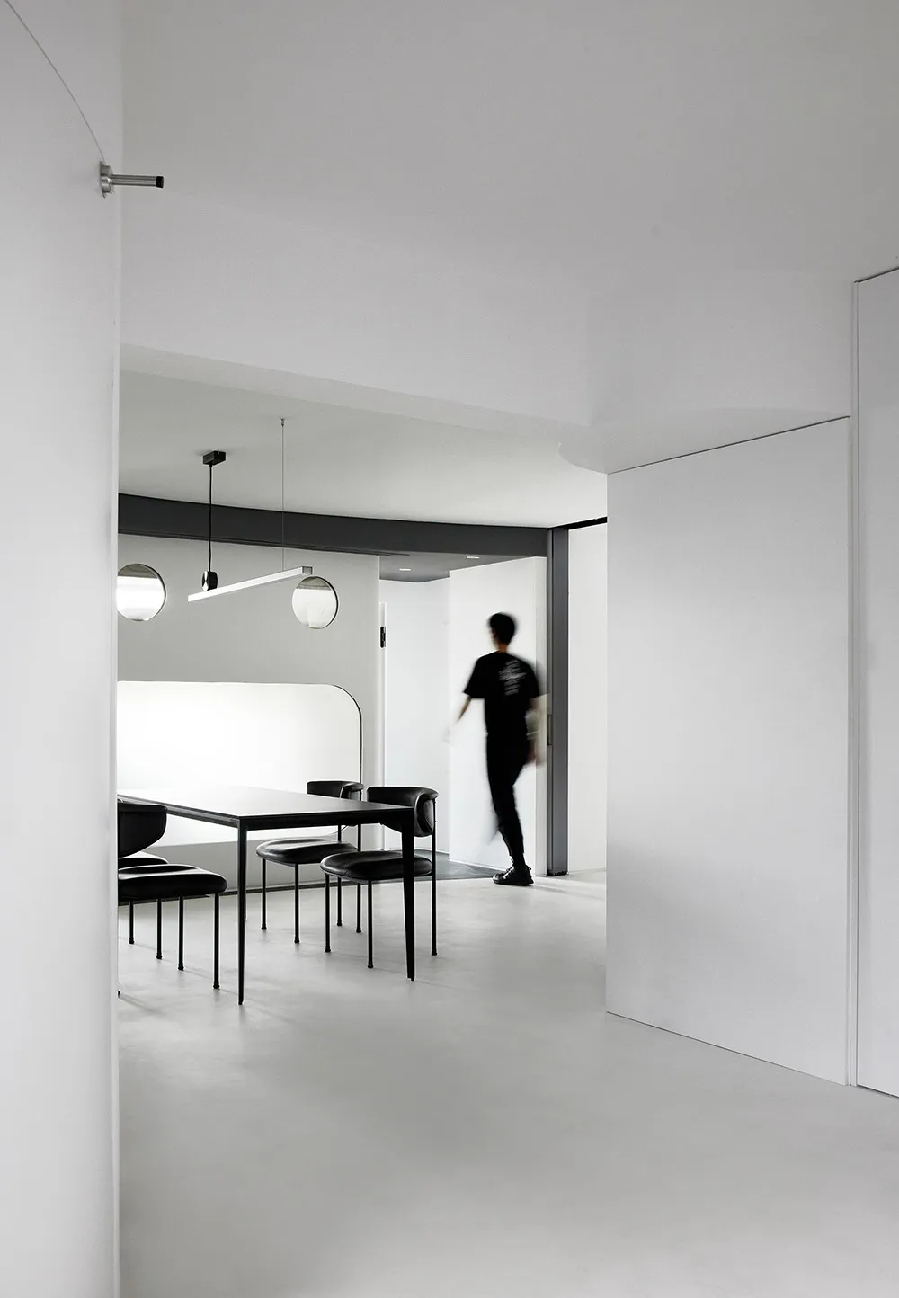 A modern minimalistic office space featuring a white concrete interior and sleek black office furniture.