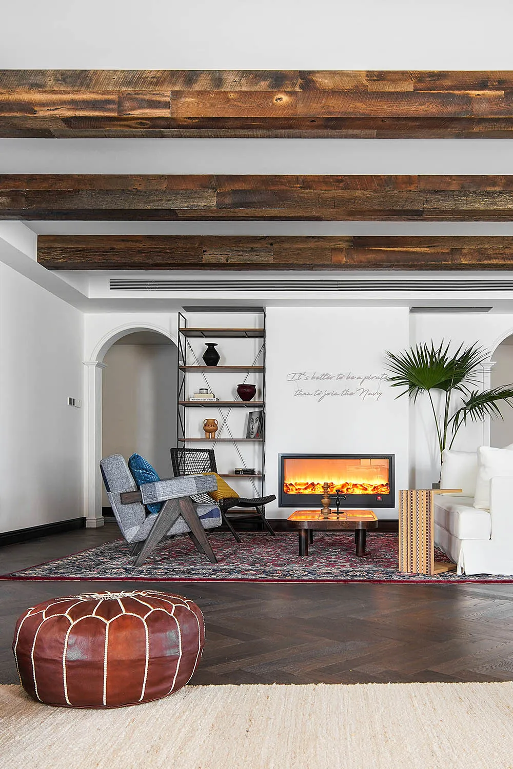 A cozy industrial-style living room with wood beams, a warm fireplace, and a mix of vintage and modern furniture.