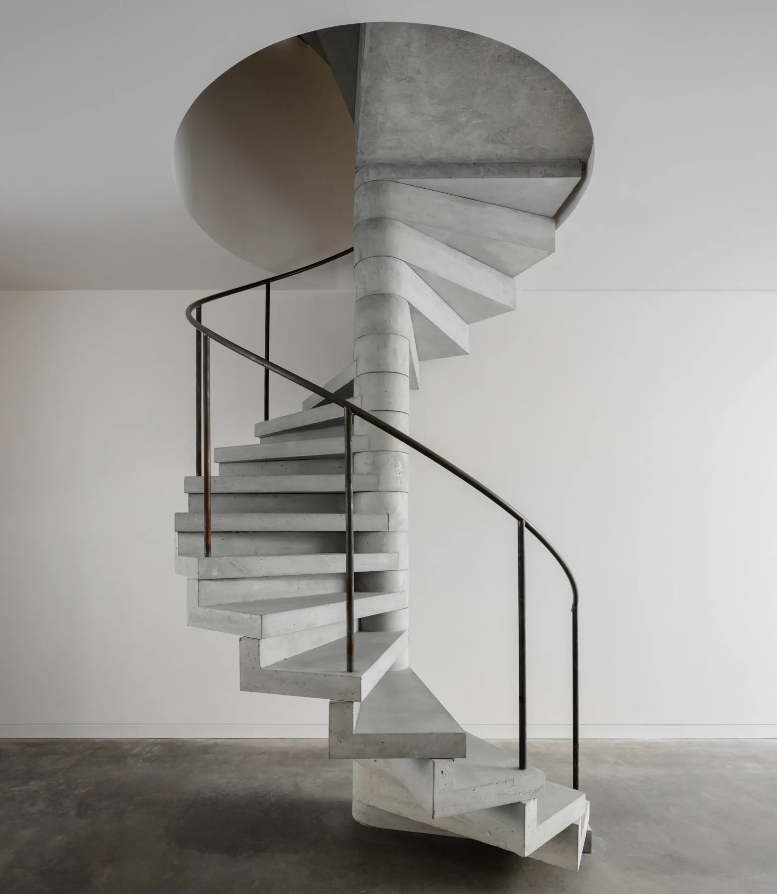 Concrete spiral staircase with black metal handrail